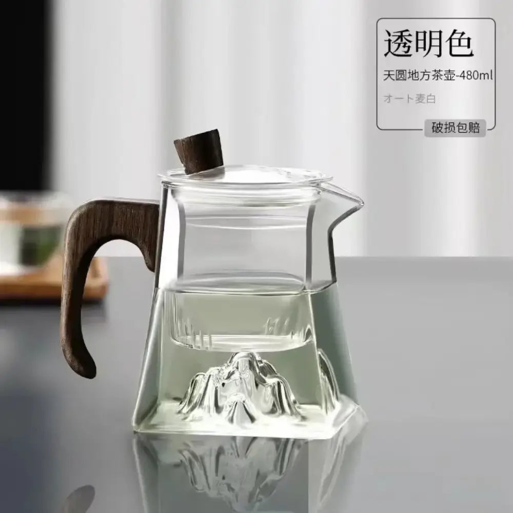 Modern square glass tea pot with dark wood handle and lid featuring mountain design molded in transparent glass base