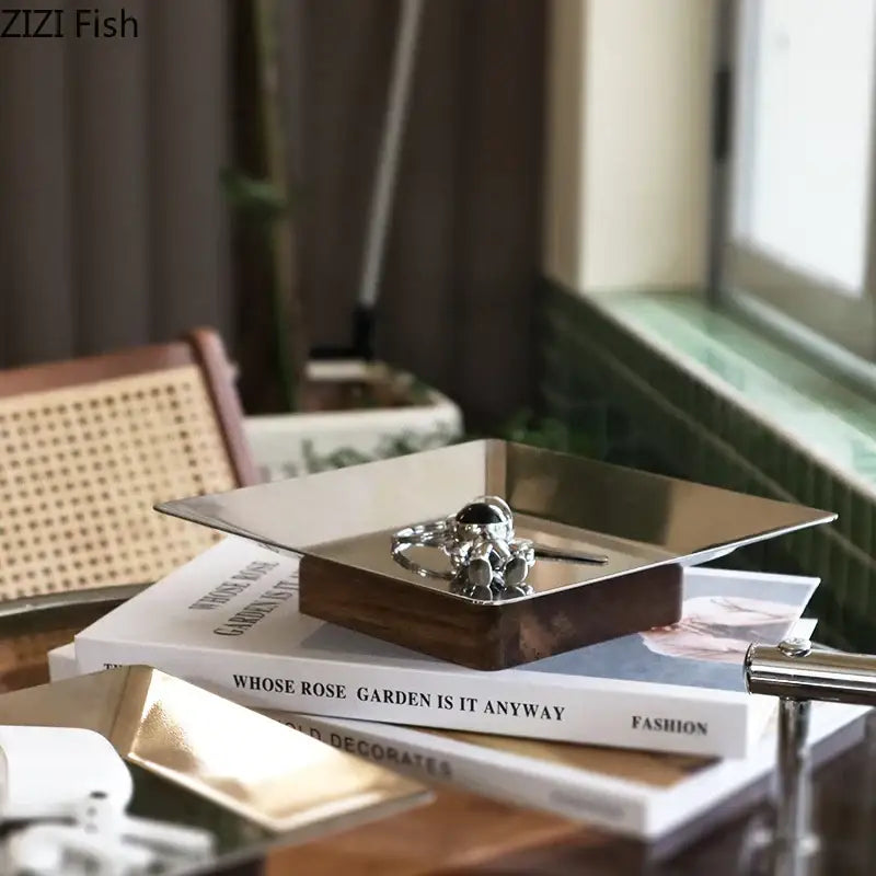 Modern square metallic fruit bowl tray with silver astronaut-themed ring display and dark wood base for living room use