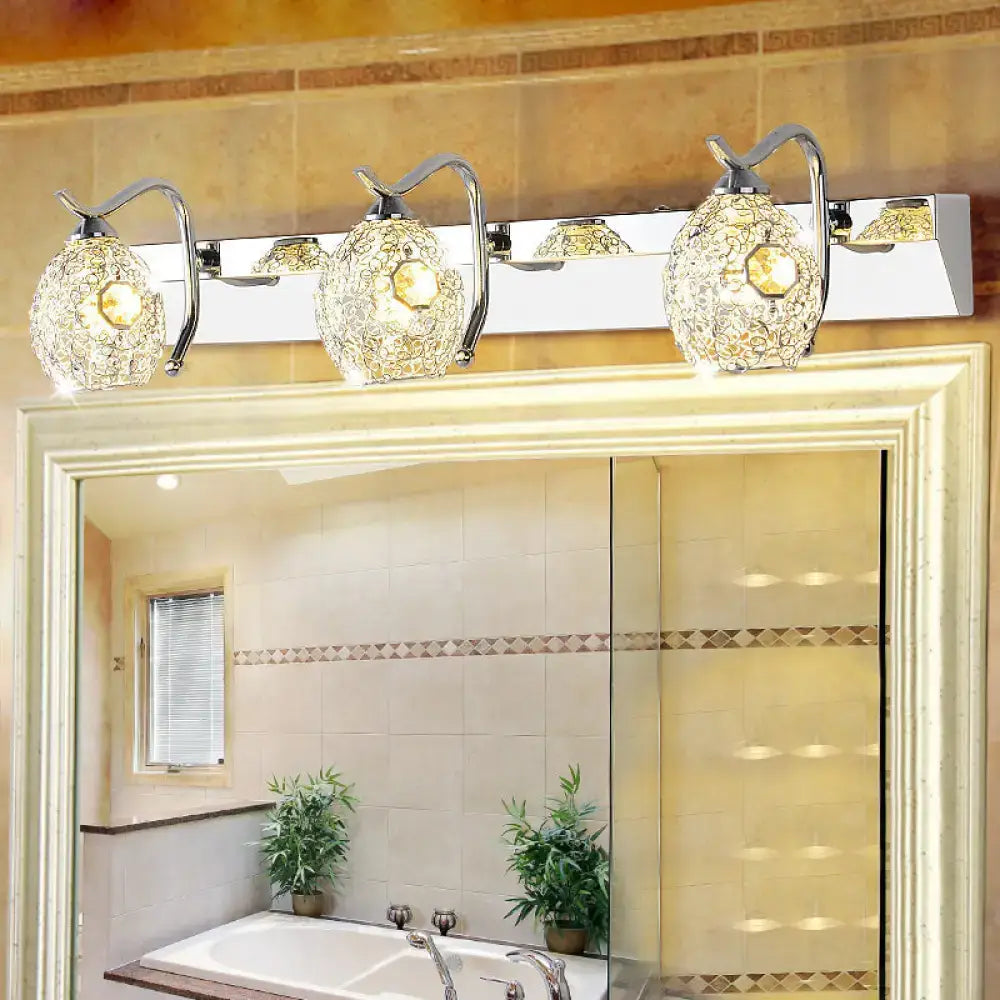 Modern stainless steel three-light wall light with chrome finish and ornate faceted crystal shades emitting warm white light