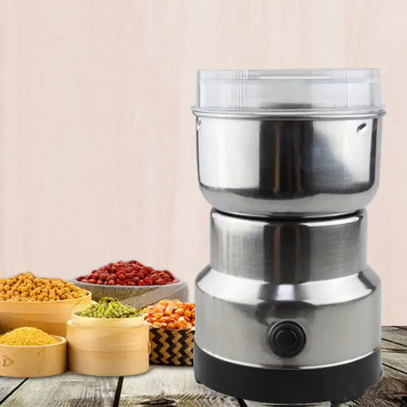 Modern stainless steel electric grinder with clear plastic lid and black base for grinding grains in kitchen