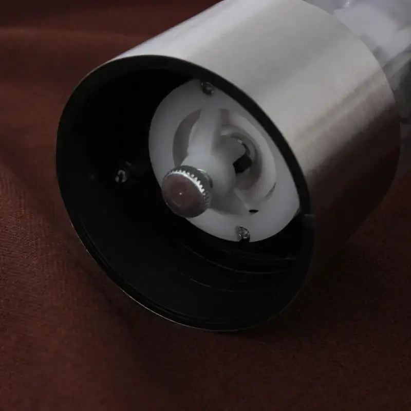 Modern stainless steel electric salt pepper grinder with clear plastic body and black interior components for kitchen use