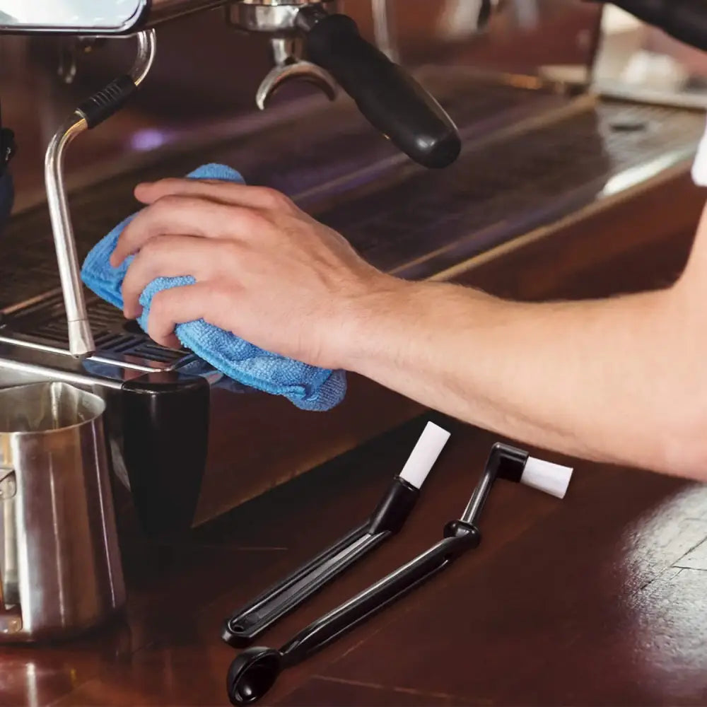 Blue microfiber cloth wiping modern stainless steel espresso machine as part of decorbites espresso machine cleaning kit
