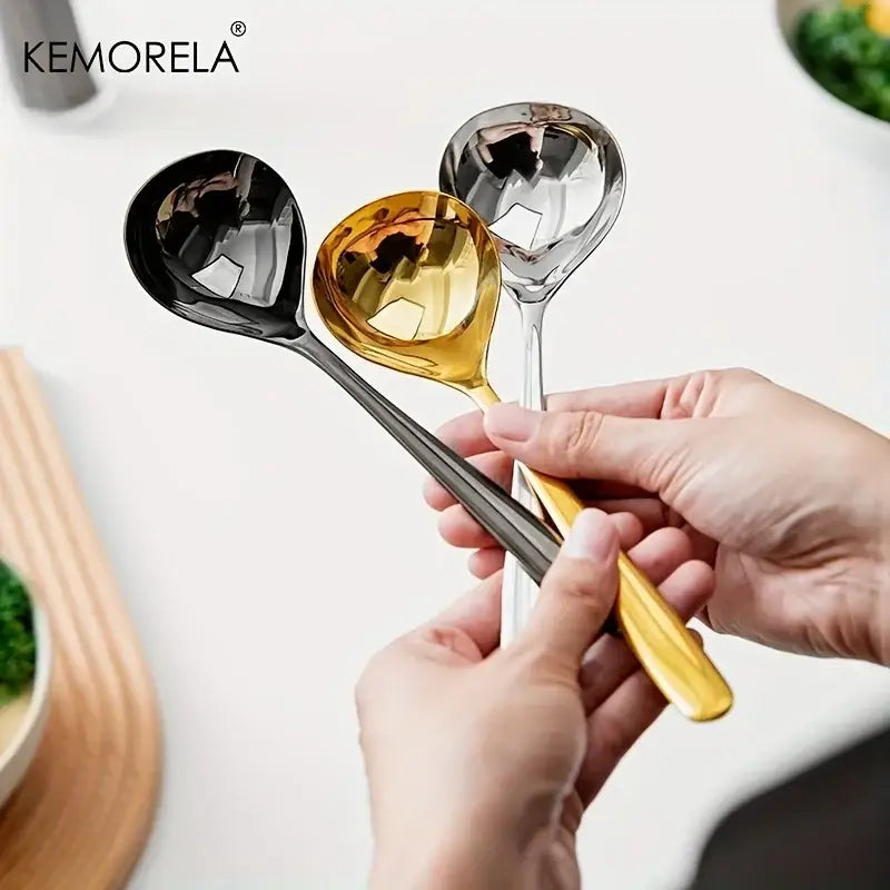 Modern stainless steel small gravy ladle set with sleek black gold and silver finishes held by a hand