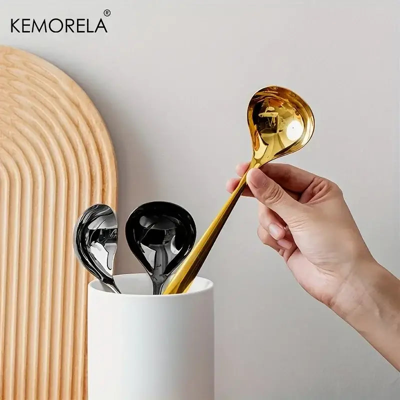 A sleek gold-colored stainless steel small gravy ladle with a glossy metallic finish held in hand for dining use
