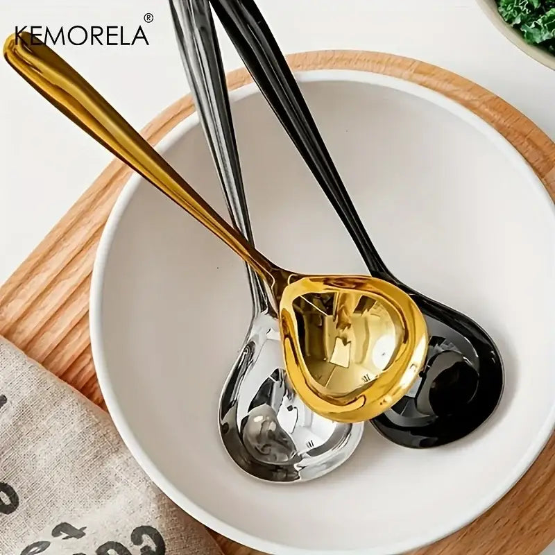 Three sleek metallic stainless steel small gravy ladles in gold silver and black rest in a white bowl for dining use