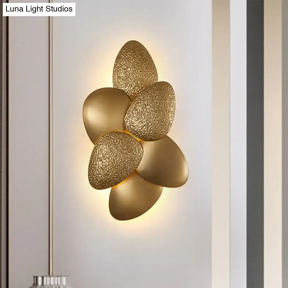 Gold-toned textured petal-shaped stainless steel squama wall light with a modern floral design for bedroom use