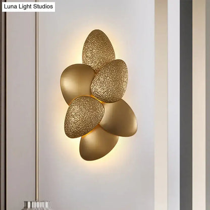 Gold-toned textured petal-shaped stainless steel squama wall light with a modern floral design for bedroom use