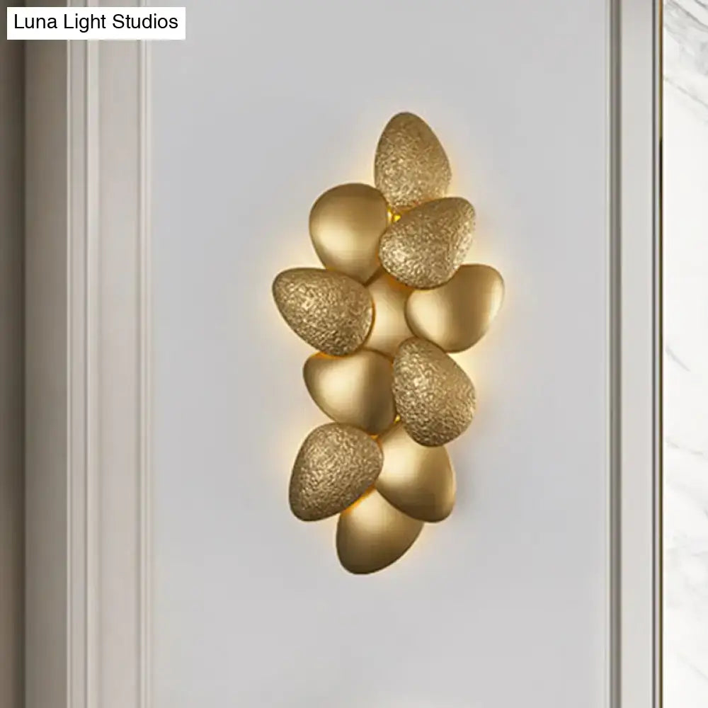 Gold-toned stainless steel squama wall light featuring a textured stone-like design with a cluster of oval-shaped elements
