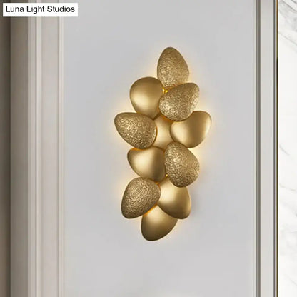 Gold-toned stainless steel squama wall light featuring a textured stone-like design with a cluster of oval-shaped elements