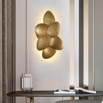 Gold-toned modern stainless steel squama wall light with textured petal design for bedroom sconce lighting
