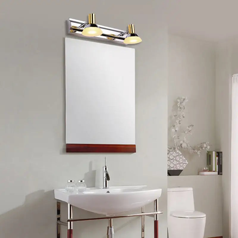 Modern stainless steel wall light with gold finish and frosted acrylic cone shade mounted above bathroom mirror