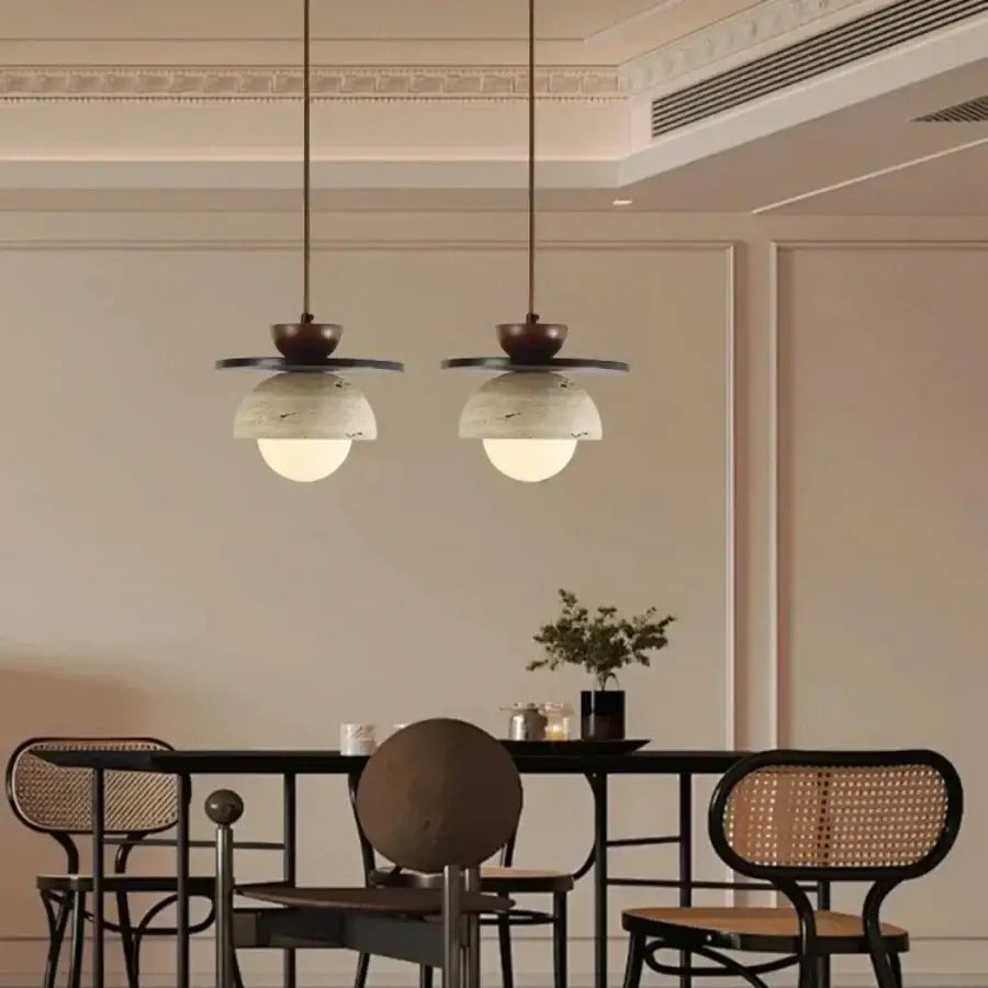 Two elegant pendant lamps with dark bronze decorbites glass ball led fixtures and marble-patterned glass shades hang above a dining table