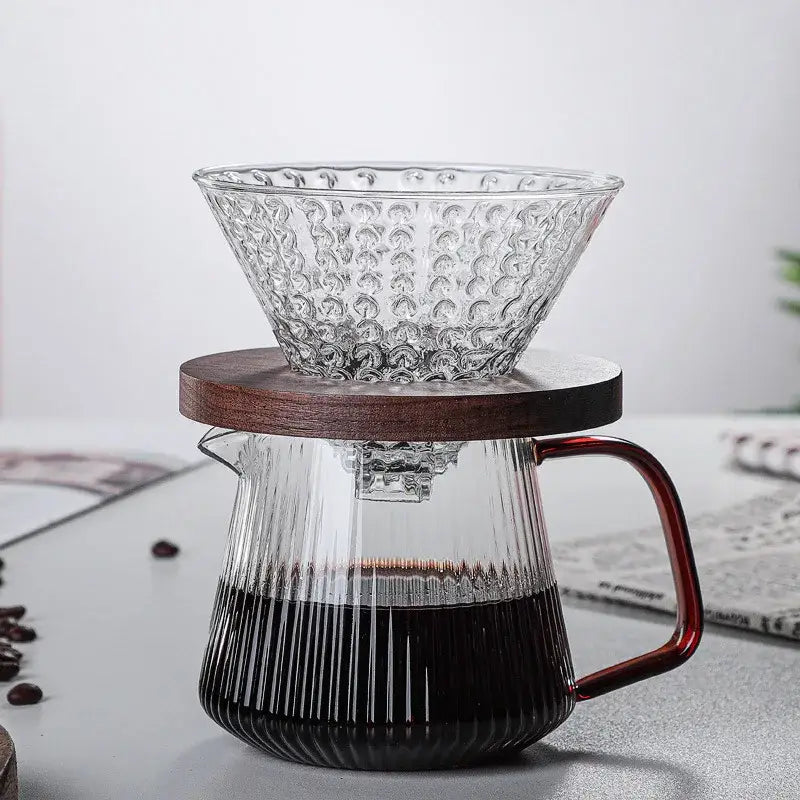 Modern striped glass coffee pot with amber handle features a clear textured glass coffee dripper over a ribbed carafe filled with coffee