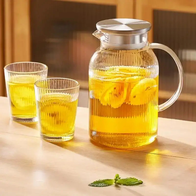 Modern striped glass cold water kettle set with clear glass pitcher filled with lemon-infused liquid and silver lid