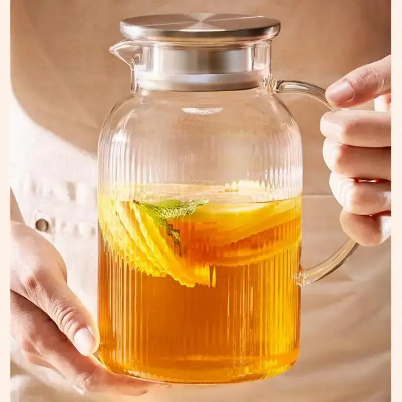 Modern striped glass cold water kettle set with vertical ridges silver lid handle filled with iced tea garnish