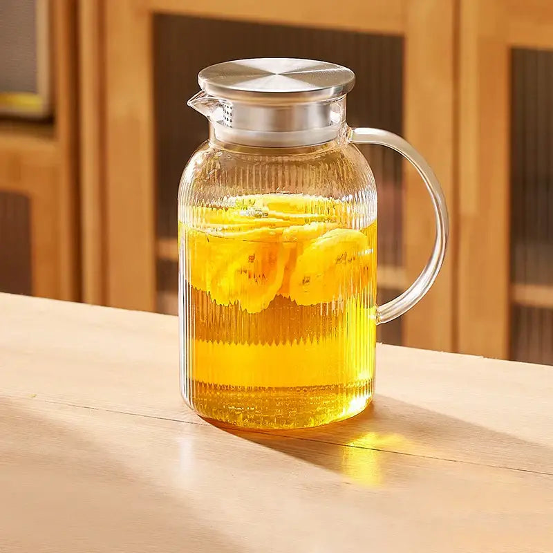 Modern striped glass cold water kettle set featuring a clear glass pitcher with silver lid and handle filled with banana beverage
