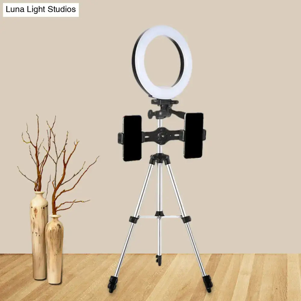Modern style black and silver led ring flash light with white illuminated band mounted on silver tripod for office use