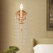 Modern style gold-toned wall sconce with clear crystal beaded strand for elegant bedroom lighting