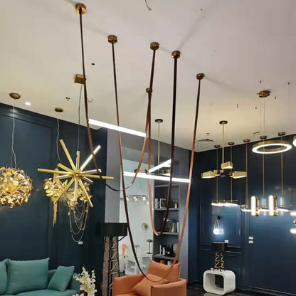 A modern tan leather and brass led tube suspension chandelier with sleek brass finish and copper-colored cords for living room