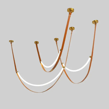 A modern tan leather and brass led tube suspension chandelier with curved straps and glowing white led tube lights
