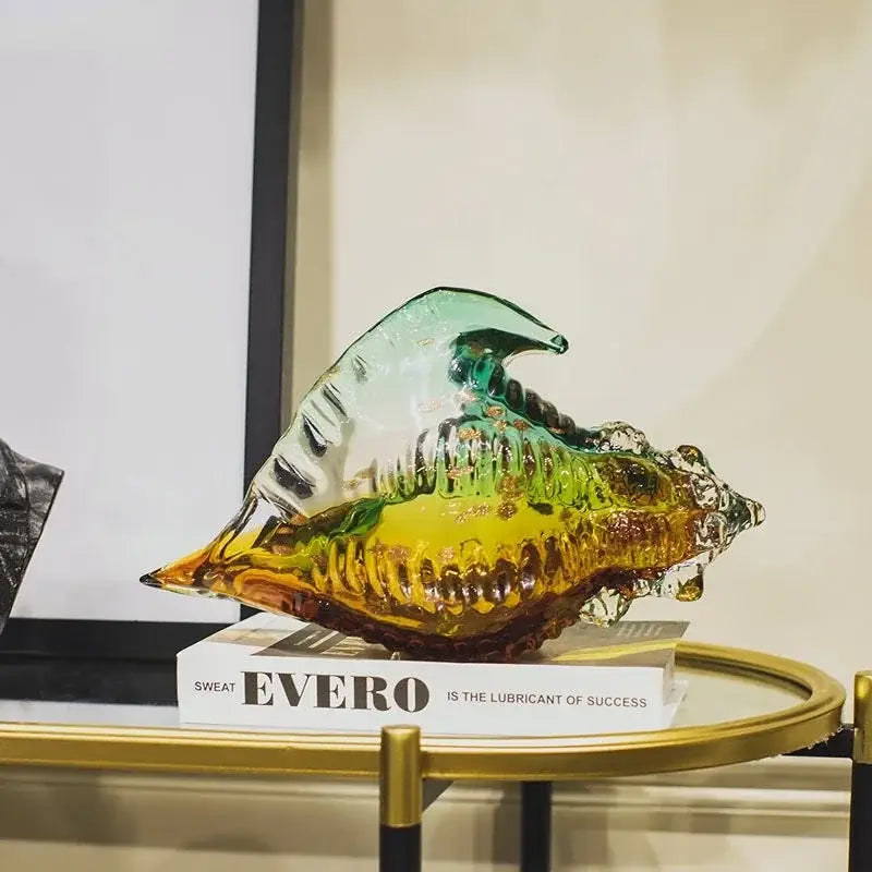 Modern teal and amber glass conch shell statue featuring iridescent translucence and intricate ridged detailing for decor