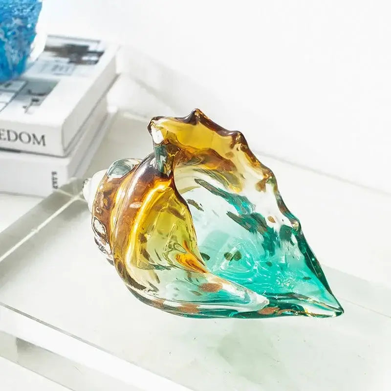 A translucent hand-blown glass conch shell statue with swirling teal and amber hues for modern living room decor