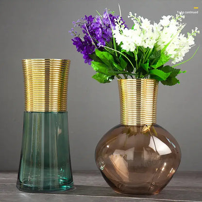 Two modern teal and amber gold metal glass vases with ribbed necks hold purple and white artificial flowers decorbites gold metal