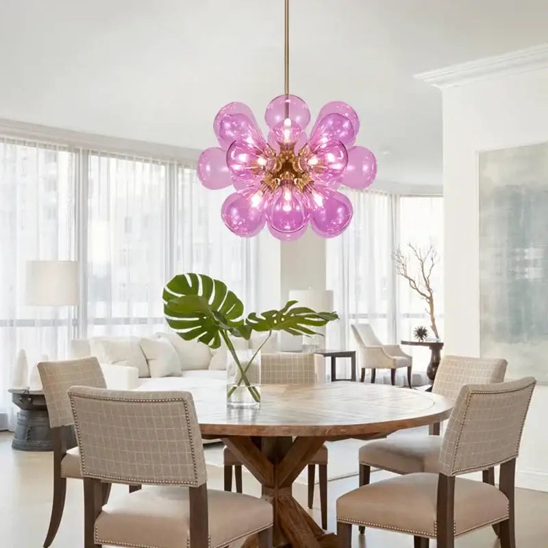 A vibrant pink glass bubble chandelier with golden central fixture and spherical bulbs as modern pendant light decorbites
