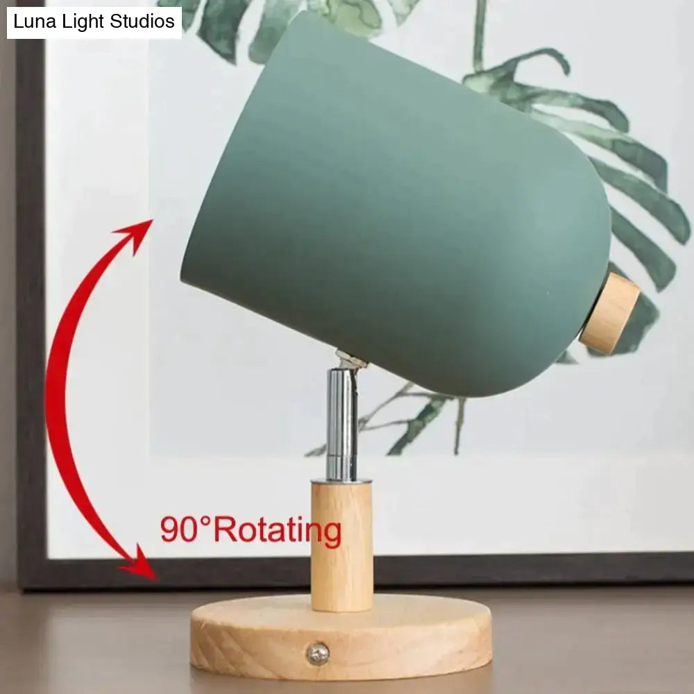 Modern teal and wood wall lamp with a matte sage green cylindrical shade and wooden base with adjustable rotating arm
