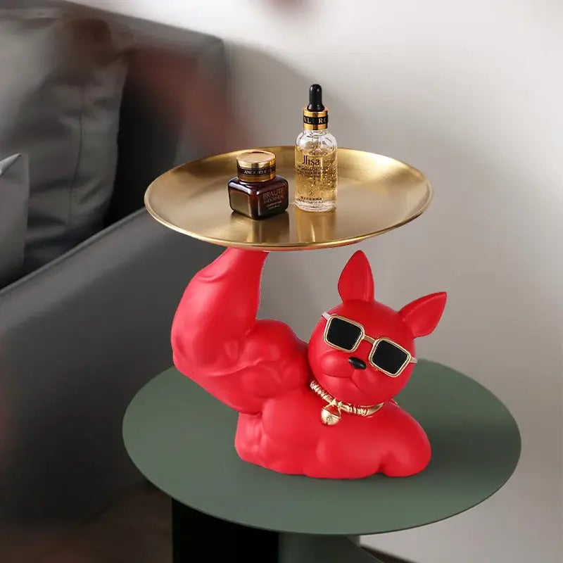 A vibrant red muscular decorbites bulldog tray with sunglasses and gold collar holding a round golden tray