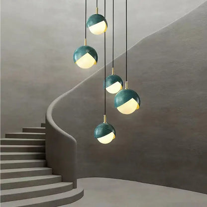 Modern teal glass and brass pendant light with sleek spherical design hanging above staircase decorbites blue copper chandelier