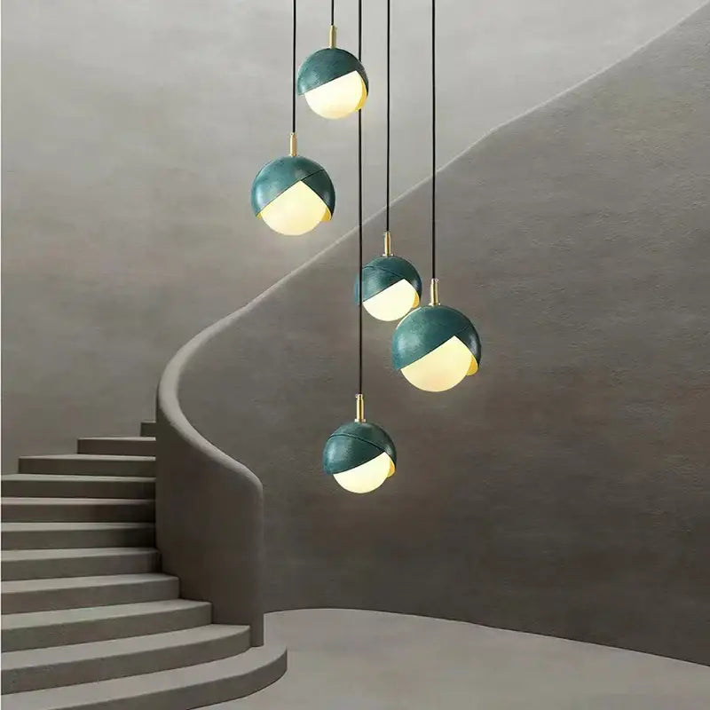 Modern teal glass and brass pendant light with sleek spherical design hanging above staircase decorbites blue copper chandelier