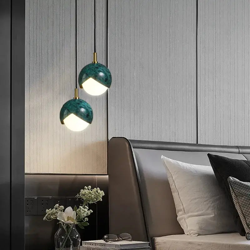 Two teal-green marble-finished pendant lights with gold hardware hanging above a bed for modern decorbites blue copper lighting