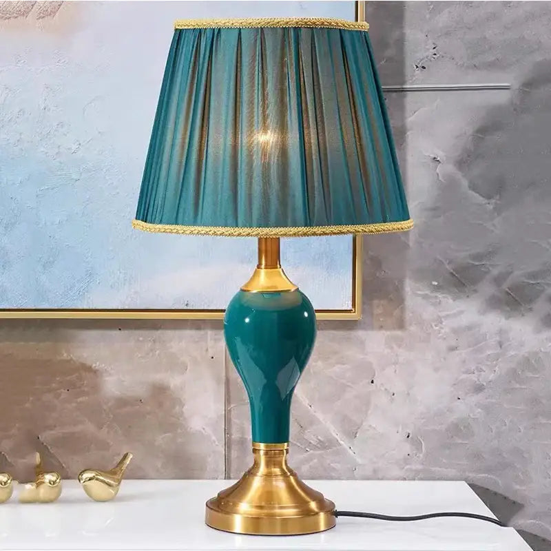 Modern teal green ceramic table lamp with gold accents and pleated fabric shade for bedroom and living room use