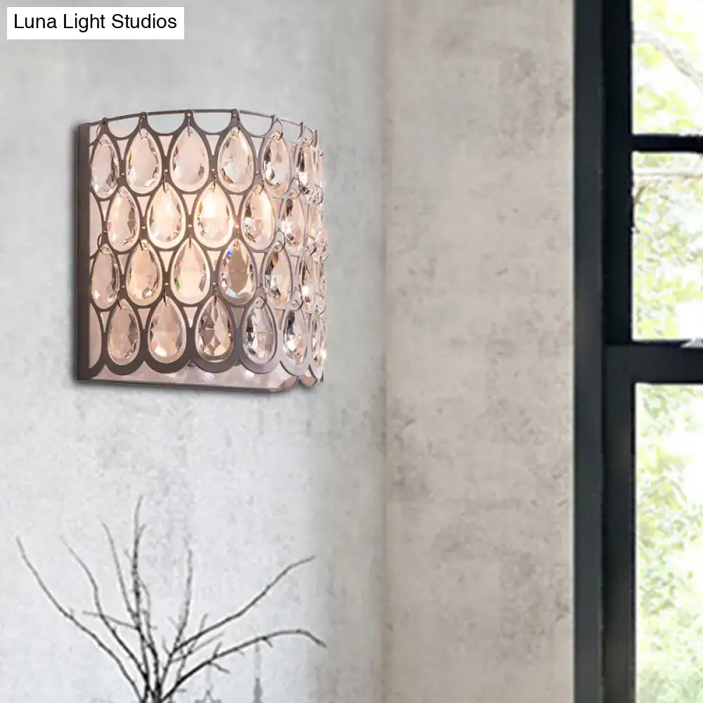 A modern wall mounted light featuring a sleek dark metal frame with faceted white teardrop crystals for bedroom use