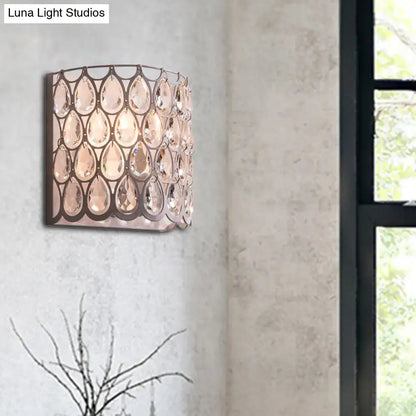 A modern wall mounted light featuring a sleek dark metal frame with faceted white teardrop crystals for bedroom use