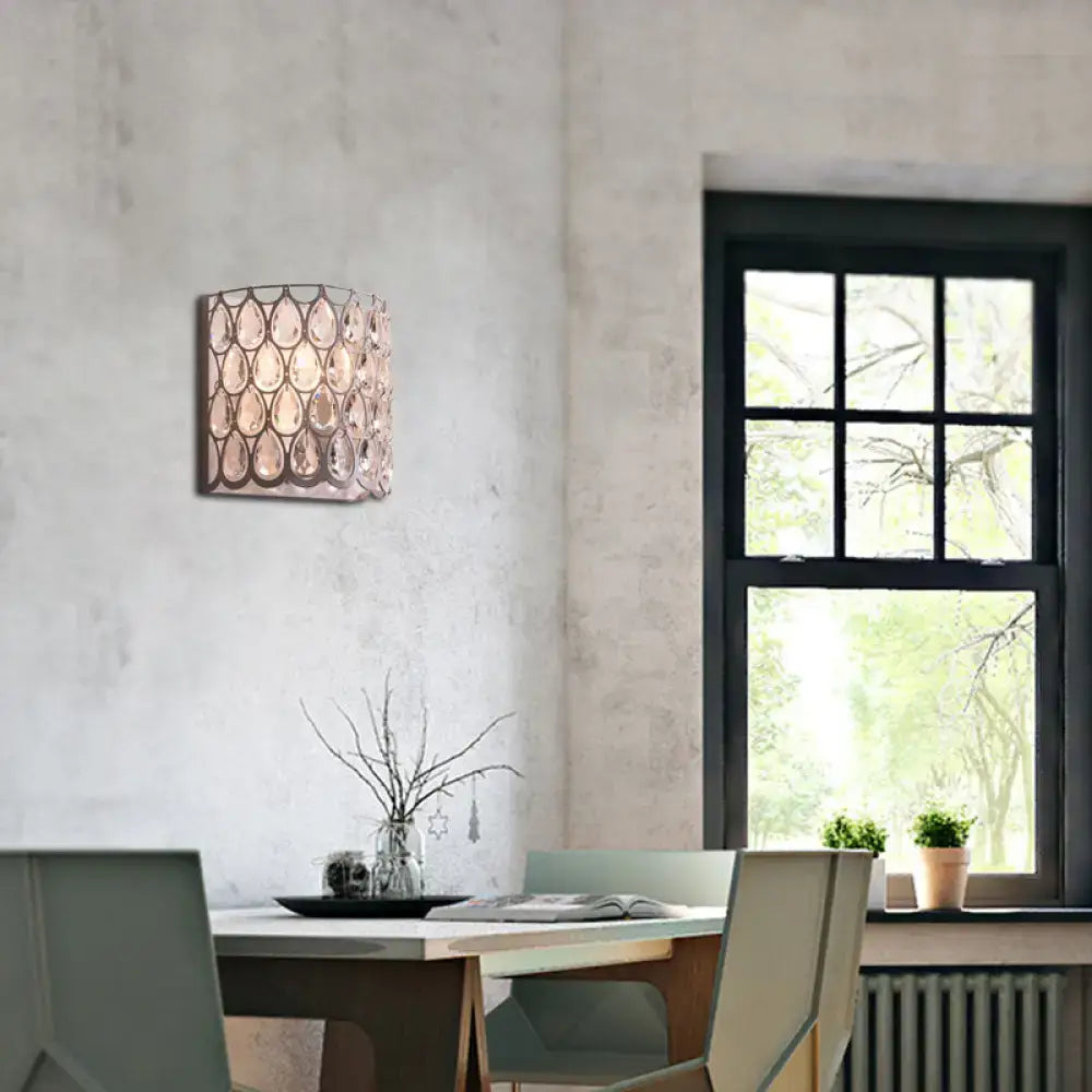 Modern teardrop crystal wall mounted light with a white cylindrical shade and hanging crystals for bedroom use