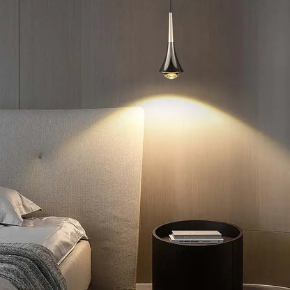 A sleek black and gold cord pendant light with metallic accent hangs above the bed casting warm illumination