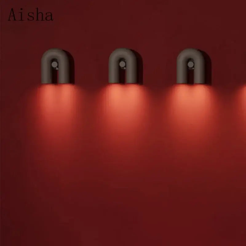 Three modern matte gray ceramic led u-shaped wall lamps emit warm red light for bedroom use