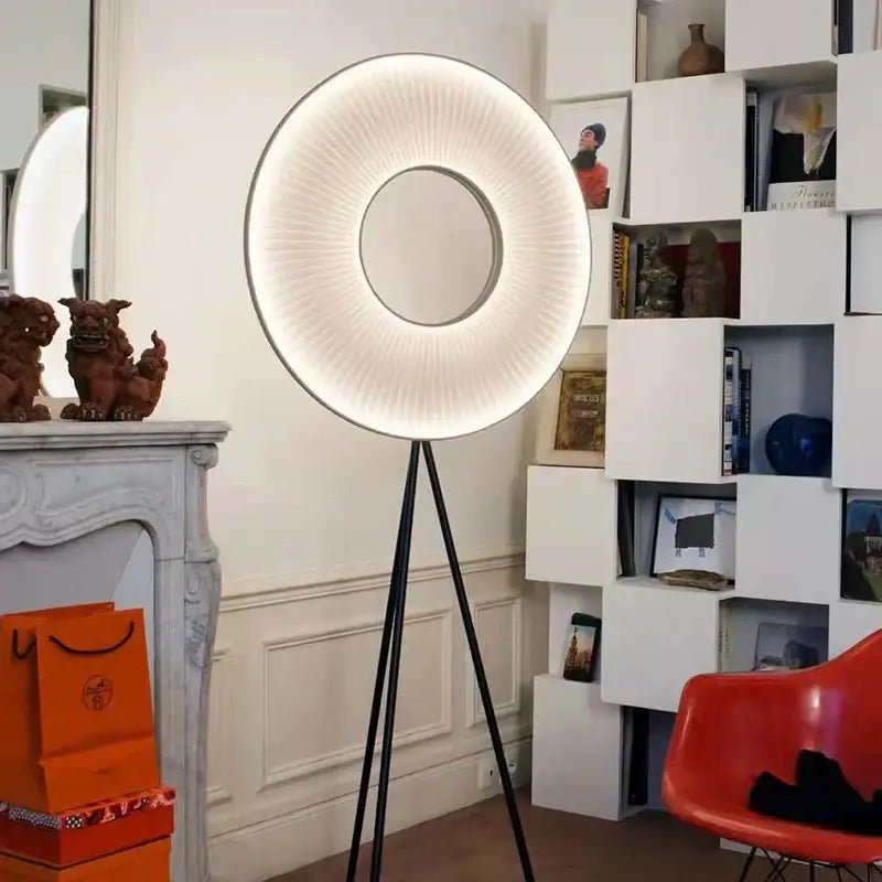 A modern dix heures round fabric pendant light with a glowing white ring and black tripod base for dining room use