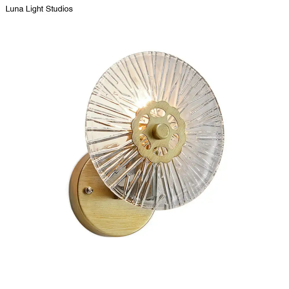Modern textured gold wall lamp with clear radially etched glass sconce and brass metal center for bedroom use