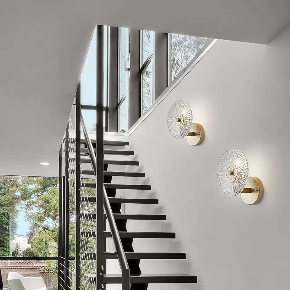 Modern textured gold wall lamp featuring gold-toned metal and clear sunburst-patterned crystal glass shades for bedroom use