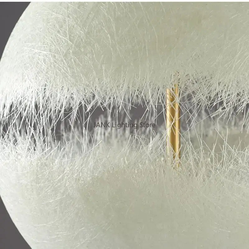 Modern textured moon pendant chandelier featuring a spherical white fiber optic lamp with a central gold-toned rod decorbites designer moon
