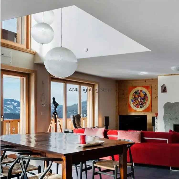 Three spherical white textured moon pendant chandelier lights hang from the ceiling in a modern living room decorbites designer moon