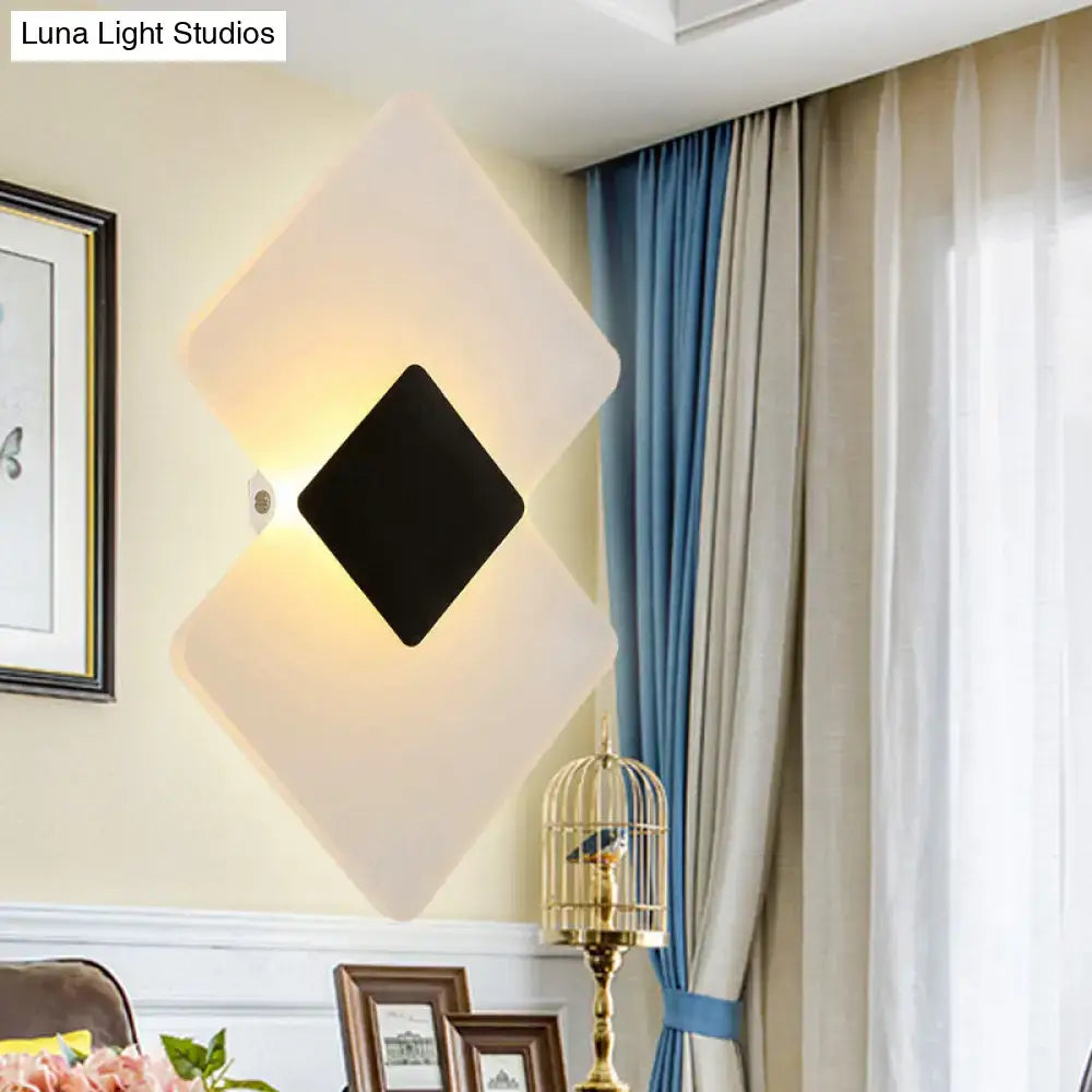 Modern textured silver and black direct wired electric diamond-shaped wall sconce with frosted white outer layer emitting warm light