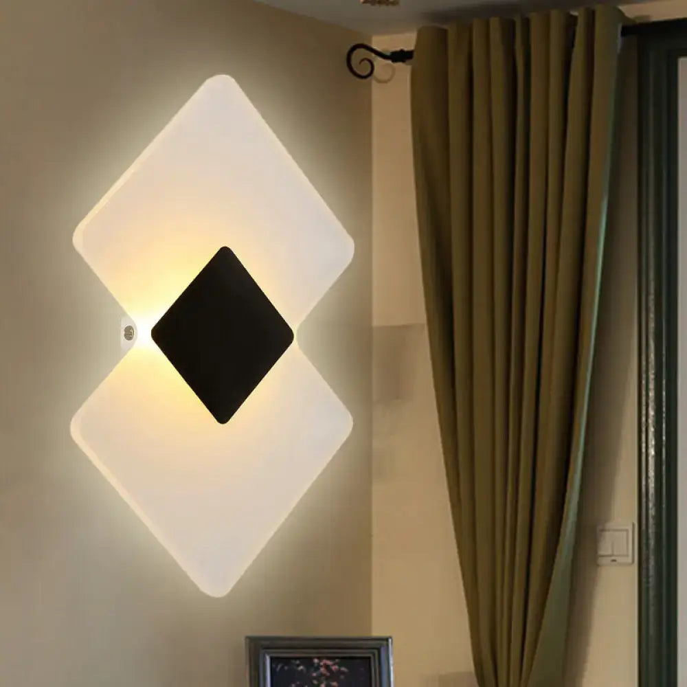 Modern textured silver and black direct wired electric wall sconce with diamond shape and frosted white panel emitting warm light