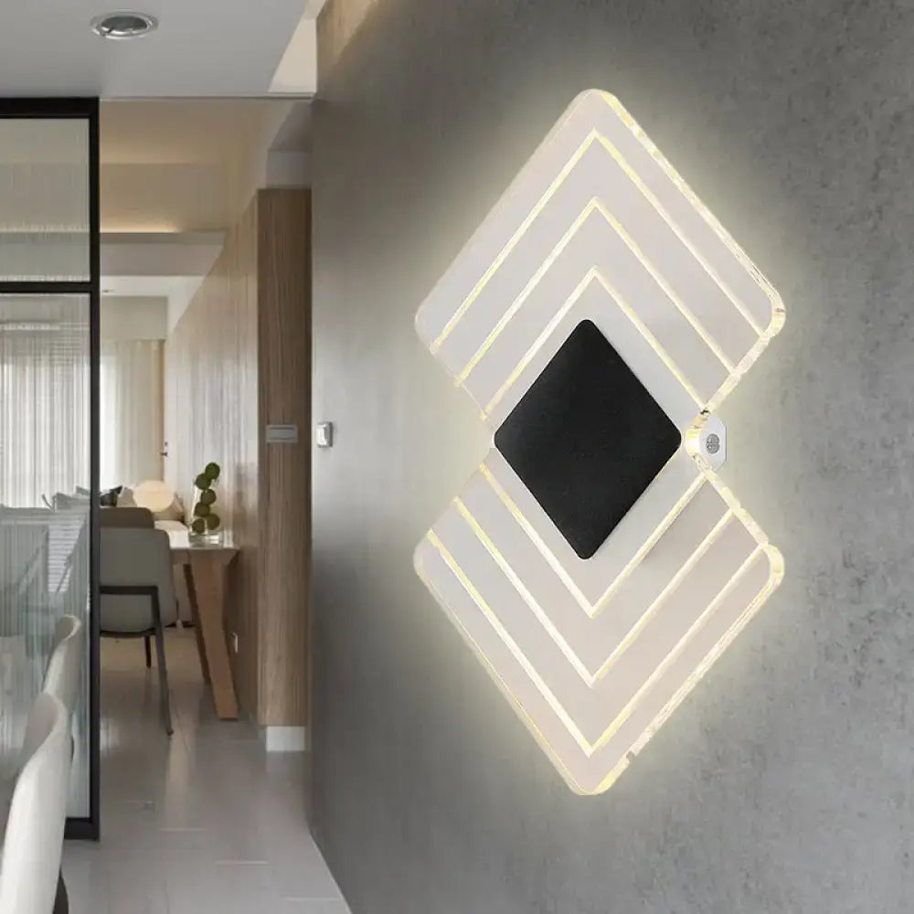 Modern textured silver and black direct wired electric wall sconce with layered acrylic panels and warm ambient light