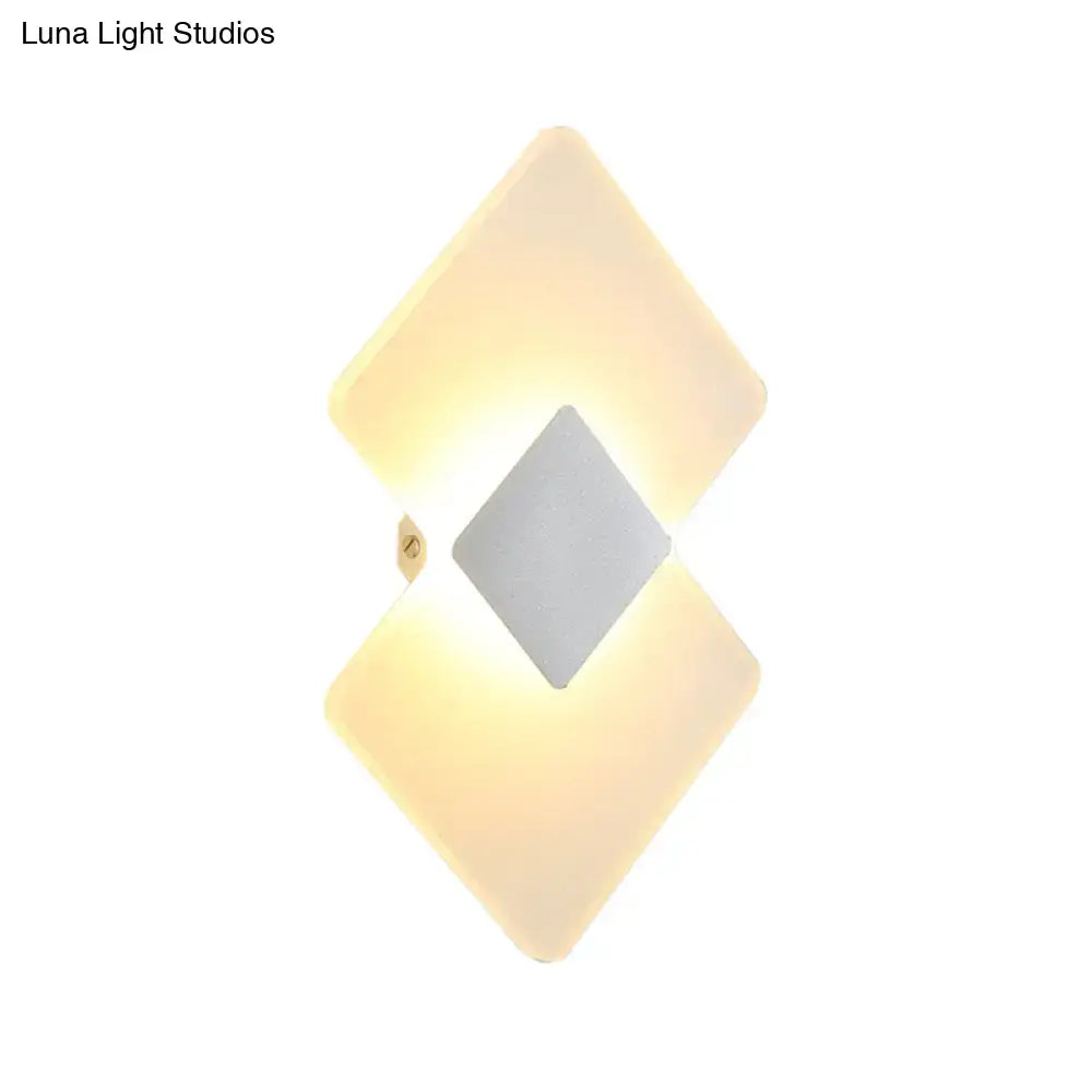 Modern textured silver and black direct wired electric wall sconce with diamond shape and warm glow for bedroom use