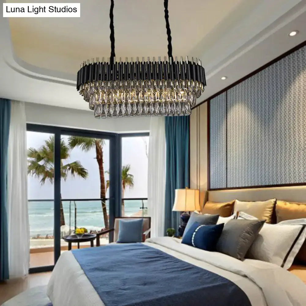 Modern tiered black and clear crystal ceiling light with cylindrical design hanging above the bed
