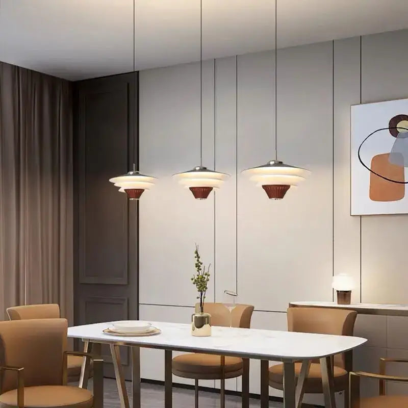 Three modern pendant lights with cream wind milk glass shades and dark bronze bases hang above a dining table